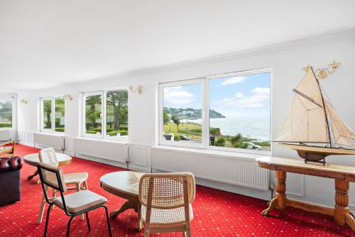 a room with a table and chairs and windows at Waters Edge Hotel Torquay in Torquay
