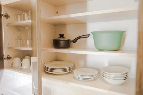 a shelf with plates and a pot and a bowl at Accra Luxury Apartments at Embassy Gardens in Accra