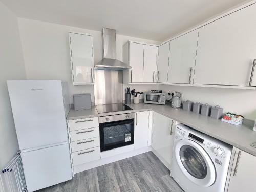 a kitchen with white cabinets and a washer and dryer at Stylish Spacious 4 Bed Townhouse near station with Parking & High Speed WiFi in Rugby