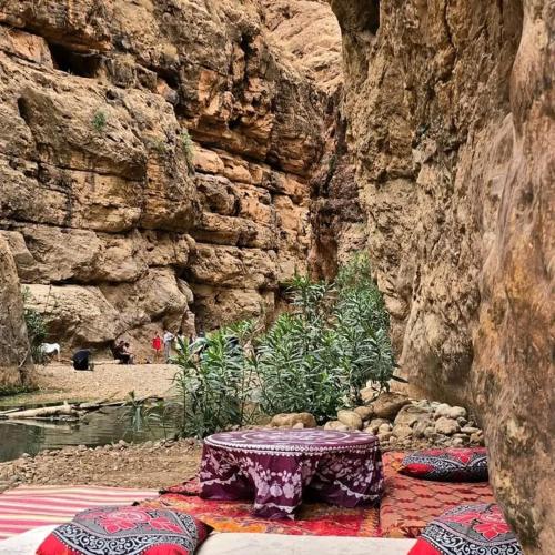 a table sitting in front of a rock wall at Dades mountain camp in Aït Oudinar
