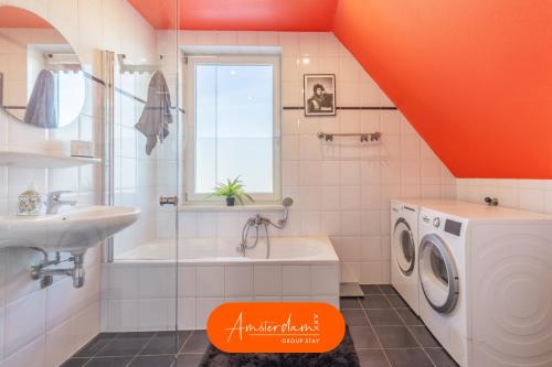 an orange bathroom with a washing machine and a sink at Amsterdam Group Stay - 26 Beds - Jacuzzi & Sauna in Zwanenburg