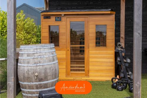 a wooden cabin with a barrel in front of it at Amsterdam Group Stay - 26 Beds - Jacuzzi & Sauna in Zwanenburg