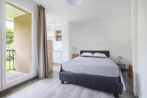 une chambre avec un lit et une grande fenêtre dans l'établissement Appartement normandie avec piscine et jardin, à Équemauville