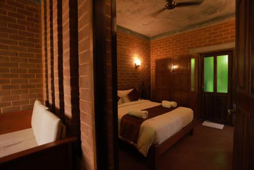 a bedroom with a bed and a brick wall at Villa Ecotiva in Puducherry