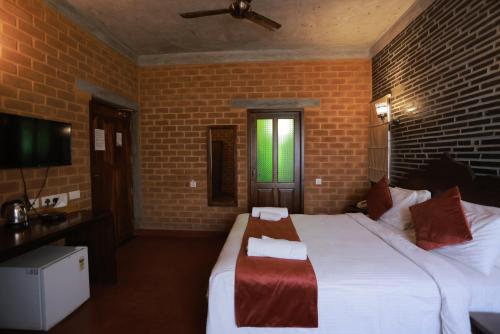 a bedroom with a large bed and a brick wall at Villa Ecotiva in Puducherry
