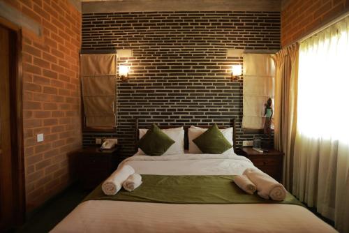 a bedroom with a large bed and a brick wall at Villa Ecotiva in Puducherry