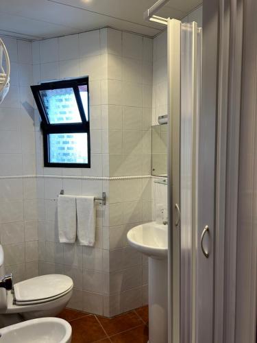 a white bathroom with a toilet and a sink at Copacabana Residencial in Costa da Caparica