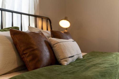 a bed with brown pillows and a lamp on it at Southern Charmer Close to Broadway Sleeps 8 in Nashville