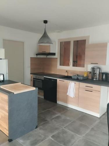 une cuisine avec des armoires en bois et un comptoir noir dans l'établissement 5a Puypérier, à Friaudour