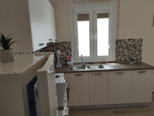 a kitchen with a sink and a window at Aloe Apartments Syros in Lazaréta