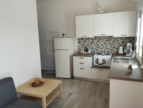 a kitchen with white cabinets and a white refrigerator at Aloe Apartments Syros in Lazaréta