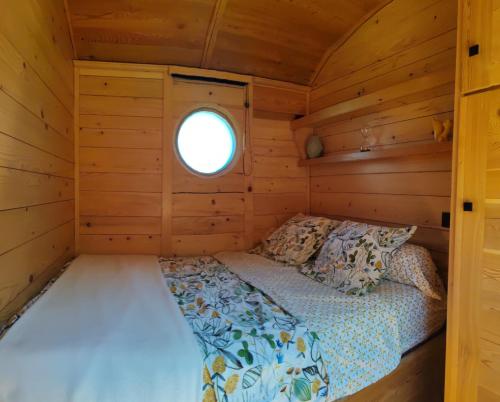 - un lit dans l'angle d'une cabine avec fenêtre dans l'établissement Gîte insolite en Champagne - Roulotte des Cahouriaux, à Nanteuil-la-Fosse