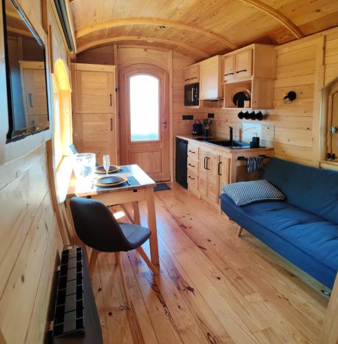 - un salon avec un canapé bleu dans une petite maison dans l'établissement Gîte insolite en Champagne - Roulotte des Cahouriaux, à Nanteuil-la-Fosse