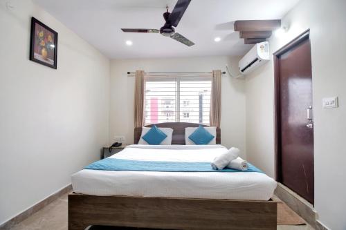 a bedroom with a bed with blue pillows and a window at beestay Hotels Visakhapatnam in Visakhapatnam