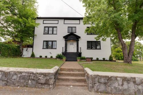 a white house with stairs leading to the front door at Bohemian Retreat Sleeps 6, two miles from Broadway! in Nashville