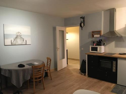 a kitchen and dining room with a table and a microwave at Appartement en Rez de jardin climatisée 2 pièces-cuisine avec terrasse et jardin in Sainte-Foy-lès-Lyon