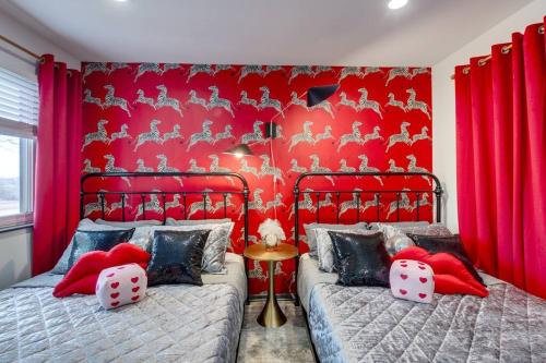 a bedroom with two beds and a red wall at Vibrant Riverfront 2BD with a Pool in Nashville