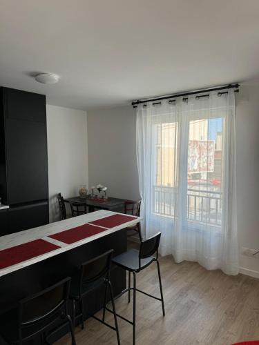 une salle à manger avec une table et des chaises et une fenêtre dans l'établissement Résidence Marceau, à Drancy