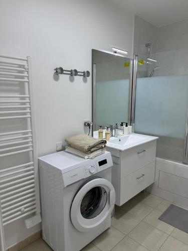 une salle de bain blanche avec une machine à laver et un lavabo dans l'établissement Résidence Marceau, à Drancy