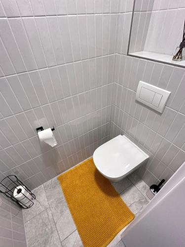 a bathroom with a white toilet and a yellow rug at Apartmány Štěpánovice in České Budějovice