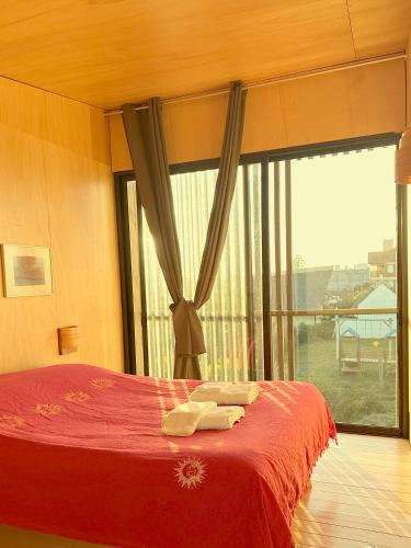 a bedroom with a red bed with a large window at CABITO B & B in La Paloma