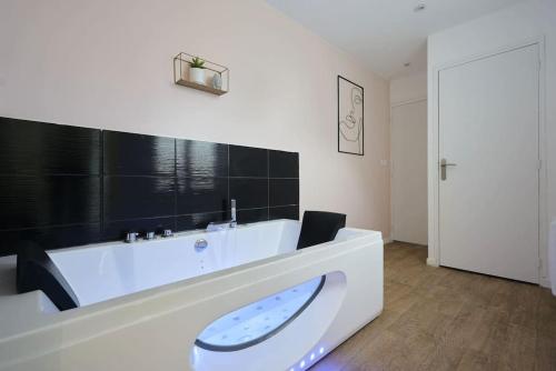 La salle de bains est pourvue d'une grande baignoire blanche. dans l'établissement Symphony - Olympe Suites & Spa Lille, Tourcoing, à Tourcoing