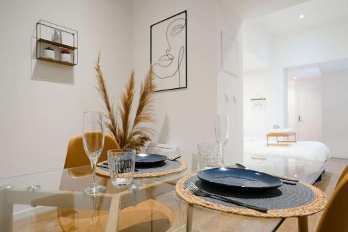 une salle à manger avec une table en verre avec des assiettes et des verres dans l'établissement Symphony - Olympe Suites & Spa Lille, Tourcoing, à Tourcoing
