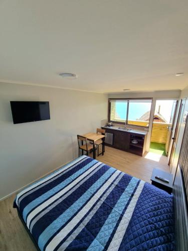 a bedroom with a bed and a flat screen tv at Al Mar Cabañas in Viña del Mar