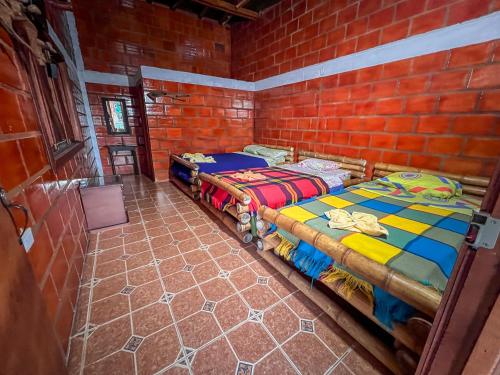two beds in a room with a brick wall at Hotel Cabañas y Glamping Colinas De San Diego in San Agustín