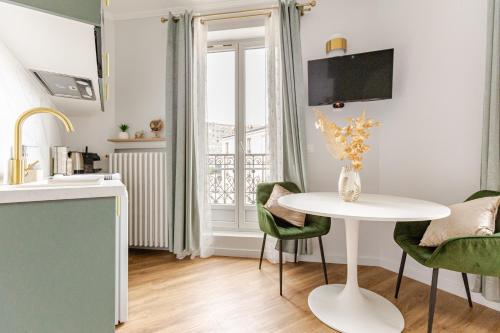une cuisine avec une table blanche et des chaises vertes dans l'établissement Studio de charme parisien, à Levallois-Perret