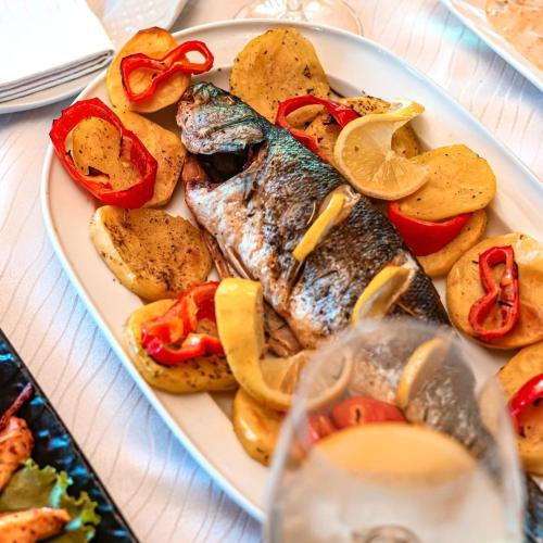 a plate of fish and potatoes and a glass of wine at Kompleksi Turistik Leonardo in Shëngjin