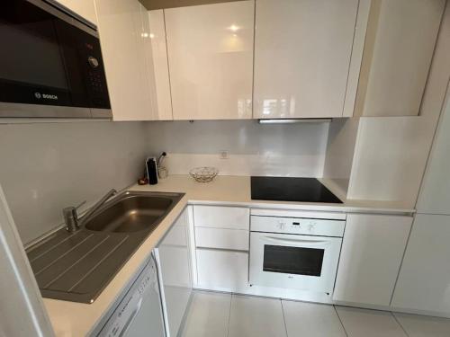 une cuisine blanche avec un évier et un micro-ondes dans l'établissement Appartement terrasse Croisette, à Cannes
