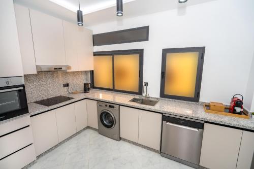 a kitchen with white cabinets and a washer and dryer at serenity stays-luxury suites & appart 2 in Tangier