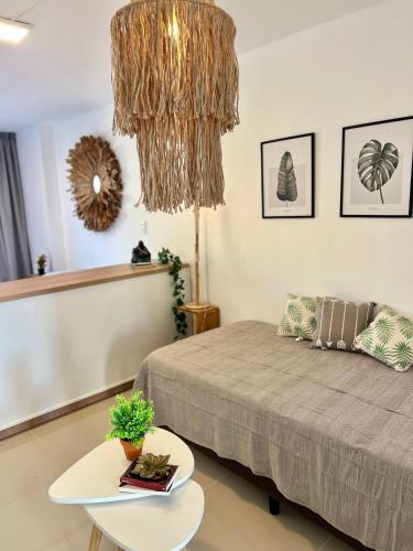 a bedroom with a bed and a table and a chandelier at Departamento céntrico funcional I Punto Alquiler in Santiago del Estero