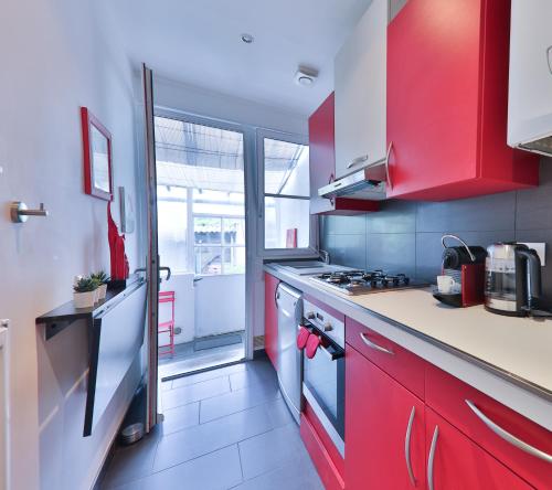 La cuisine est équipée de placards rouges et d'un four avec plaques de cuisson. dans l'établissement Villa Emma , maison classée 3 étoiles au centre de tout avec jardin clos à Châtellerault, à 20 mn Futuroscope&Aquascope, à Châtellerault