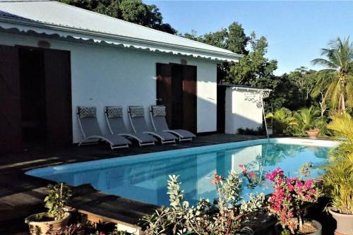 Una piscina con sillas al lado de una casa. en Tikazbleue 2024 Maison entière chez l'habitant, en Sainte-Rose