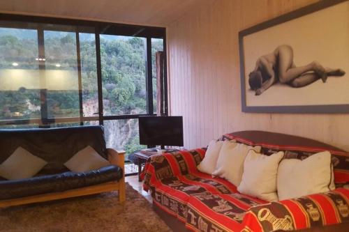 a living room with a couch and a bed and a window at Casa cerro en shangrila lodge con piscina in Puente Negro