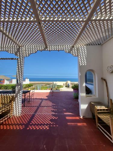 a patio with a pergola with a view of the ocean at Dar janoub in Aït Raïs Aomar