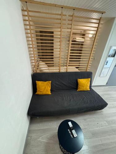 - un canapé noir avec deux oreillers jaunes dans l'établissement Le Marceau - Appartement confortable à Aubagne, à Aubagne