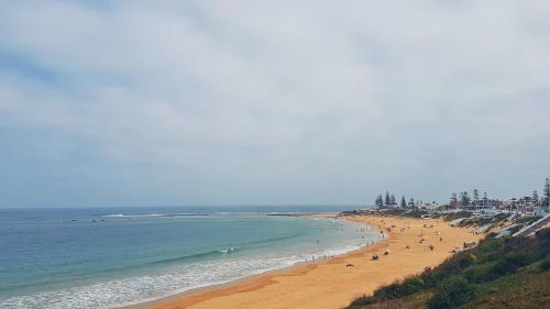a beach with people on the sand and the ocean at Villa Mly Saïd in Sidi Bouzid