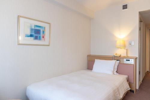 a bedroom with a white bed and a picture on the wall at ホテルレイクアルスターアルザ泉大津 in Izumiotsu