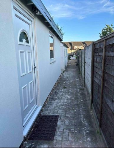 an alley with a white door and a fence at Cozy cabin independent ensuite in Guildford