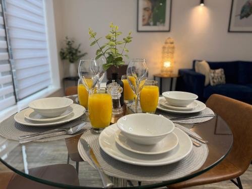 a glass table with plates and glasses of orange juice at Central City Two-Bedroom in Swindon