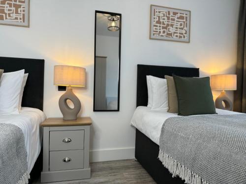 two beds in a bedroom with two lamps and a mirror at Central City Two-Bedroom in Swindon