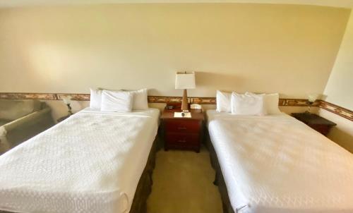 a room with two beds and a lamp on a table at August Lodge Cooperstown in Hartwick Seminary