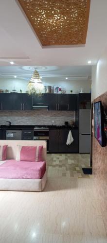 een woonkamer met een roze bank en een keuken bij Chambre Surf Oubaha Tamrakht Taghazout in Agadir