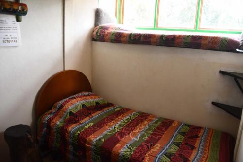 a bed in a room with a blanket on it at La Cigarra Casa de Huéspedes in Salento