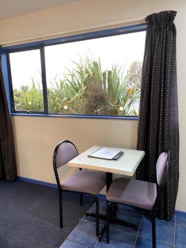 a table and two chairs in front of a window at Haast River Motels & Holiday Park in Haast