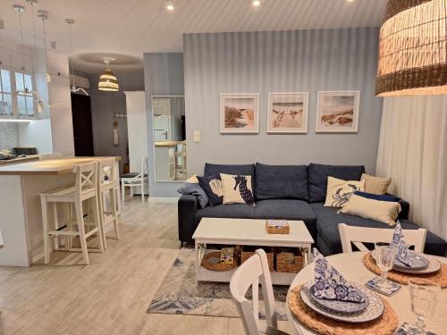 a living room with a blue couch and a kitchen at WYSPA MEW - apartament PREMIUM z prywatnym ogrodem, 150 m od plaży in Gąski