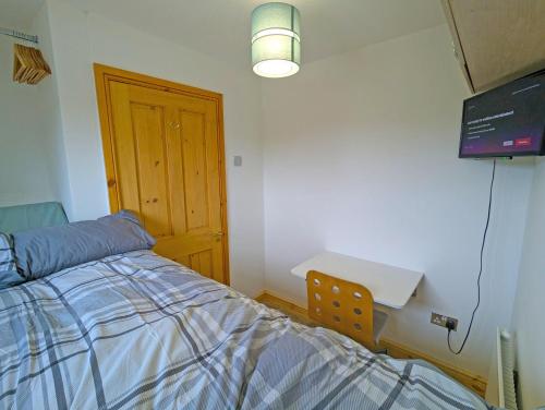 a bedroom with a bed and a desk and a table at Cosy Single Room l Smart TV l 5 Minute Walk from Train Station in Bolton